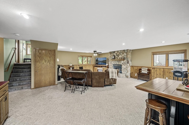 3894 Kestrel St SW, Prior Lake, MN 55372 - living room with stairs, a stone fireplace, carpet flooring, ceiling fan, and a wainscoted wall
