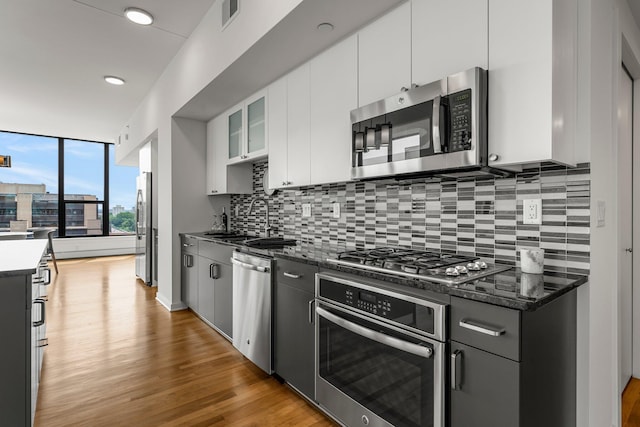 740 Portland Ave Unit 801, Minneapolis, MN 55415 - kitchen with stainless steel appliances, decorative backsplash, light wood finished floors, white cabinetry, and glass insert cabinets