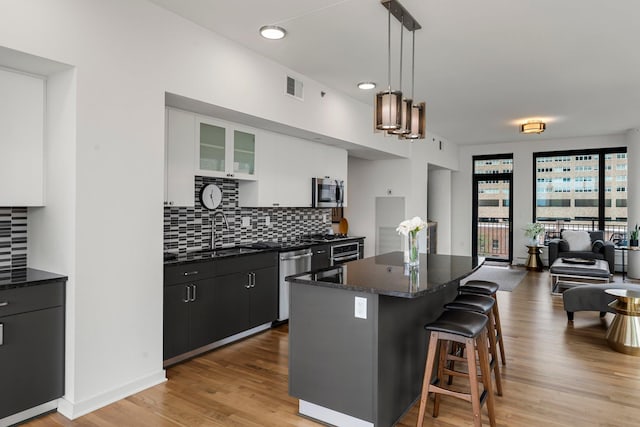 740 Portland Ave Unit 801, Minneapolis, MN 55415 - kitchen with stainless steel appliances, a kitchen island, a breakfast bar area, backsplash, and white cabinets