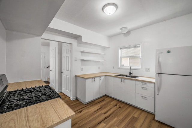 2931 Lyndale Ave N, Minneapolis, MN 55411 - kitchen with freestanding refrigerator, black range with gas stovetop, white cabinets, wood finished floors, and open shelves