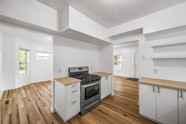 2931 Lyndale Ave N, Minneapolis, MN 55411 - kitchen featuring stainless steel gas range oven, wood counters, light wood-type flooring, open shelves, and white cabinetry
