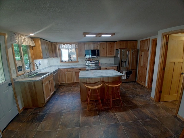 1959 79th St, Georgetown Twp, WI 54853 - kitchen featuring stainless steel appliances, light countertops, a kitchen island, a textured ceiling, and a kitchen bar