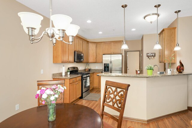 1816 Commonwealth Blvd, Chanhassen, MN 55317 - kitchen featuring stainless steel appliances, light wood-style floors, a peninsula, pendant lighting, and a chandelier