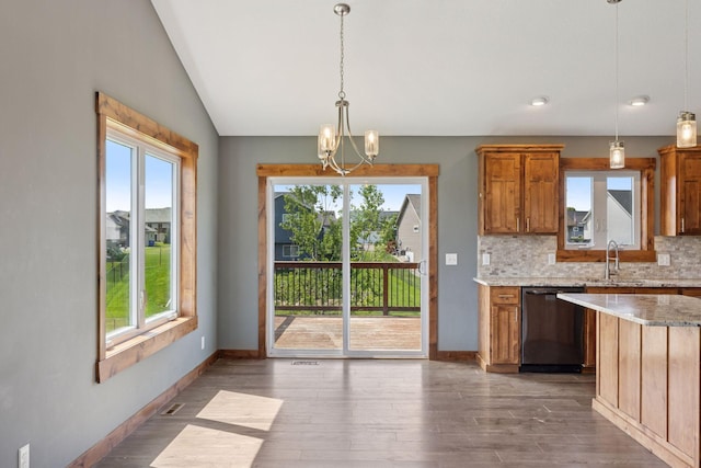 1664 Otter Way, New Richmond, WI 54017 - kitchen featuring stainless steel dishwasher, plenty of natural light, brown cabinetry, tasteful backsplash, and vaulted ceiling