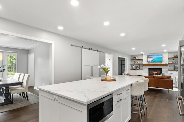 1541 Wexford Ct, Eagan, MN 55122 - kitchen with stainless steel microwave, white cabinetry, dark wood-style flooring, a kitchen island, and recessed lighting