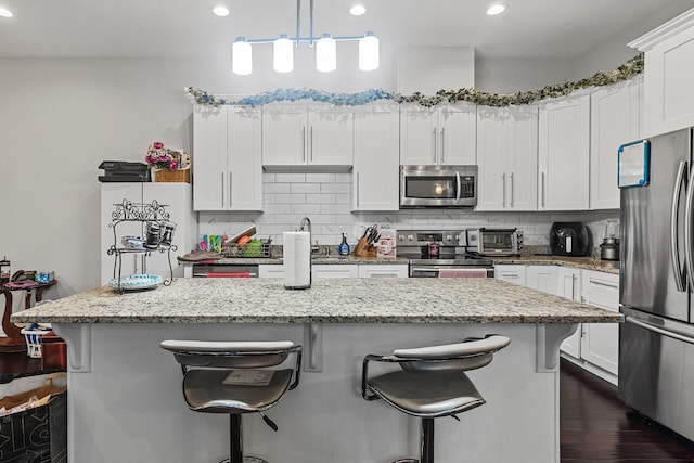 1227 Dupont Ln N, Brooklyn Park, MN 55444 - kitchen featuring appliances with stainless steel finishes, white cabinets, decorative backsplash, a breakfast bar, and recessed lighting
