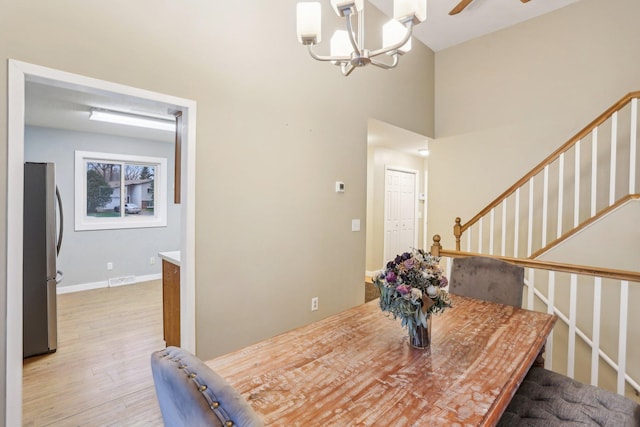 7467 Meadowwood Ct, Brooklyn Park, MN 55444 - dining area featuring light wood-style floors, a chandelier, a high ceiling, and stairway