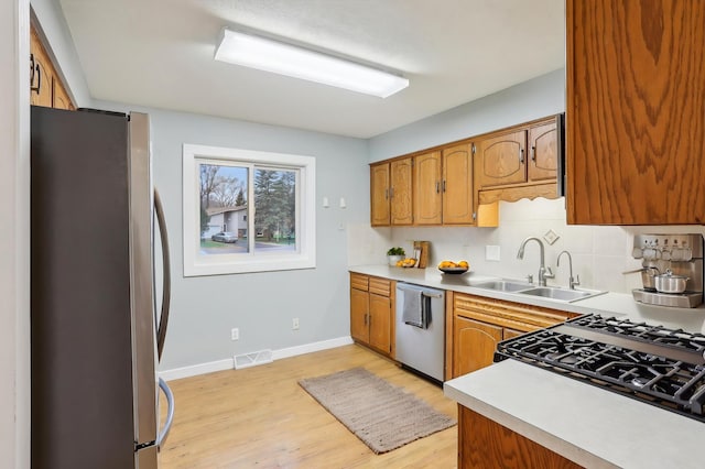7467 Meadowwood Ct, Brooklyn Park, MN 55444 - kitchen featuring appliances with stainless steel finishes, light wood finished floors, light countertops, and brown cabinetry