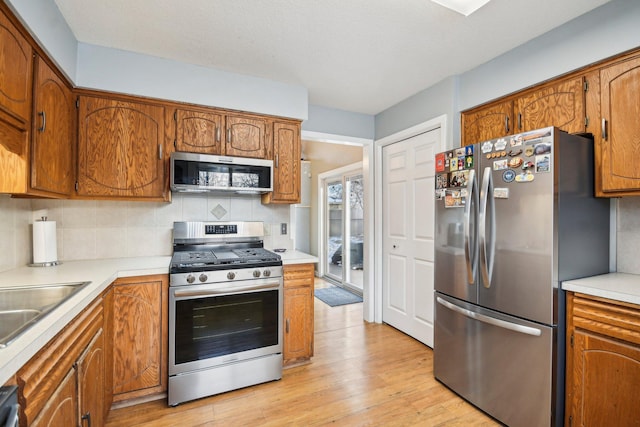 7467 Meadowwood Ct, Brooklyn Park, MN 55444 - kitchen featuring stainless steel appliances, decorative backsplash, and brown cabinetry