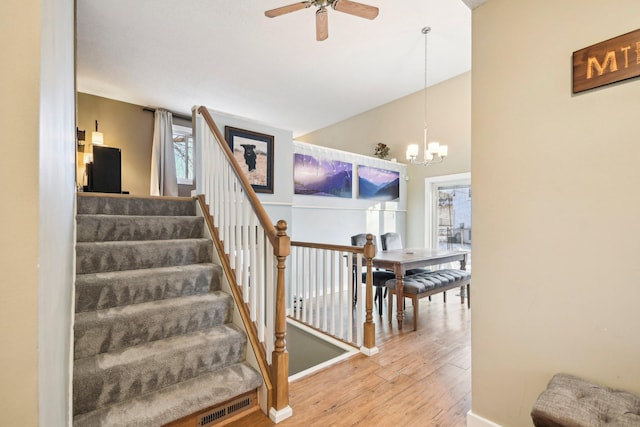 7467 Meadowwood Ct, Brooklyn Park, MN 55444 - stairs featuring wood finished floors, ceiling fan, high vaulted ceiling, and a chandelier