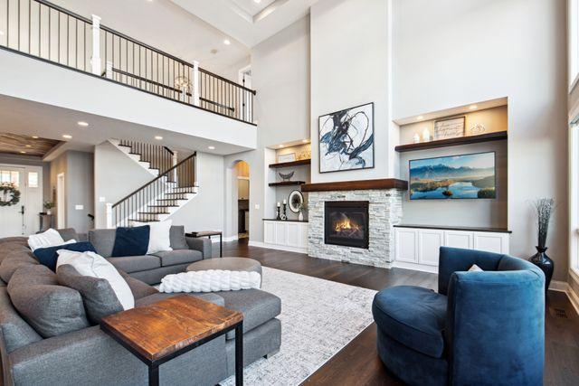 19803 Jersey Ave, Lakeville, MN 55044 - living area with stairs, dark wood-style floors, a towering ceiling, a fireplace, and recessed lighting