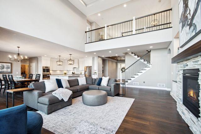 19803 Jersey Ave, Lakeville, MN 55044 - living area featuring a towering ceiling, stairs, dark wood finished floors, a fireplace, and a chandelier