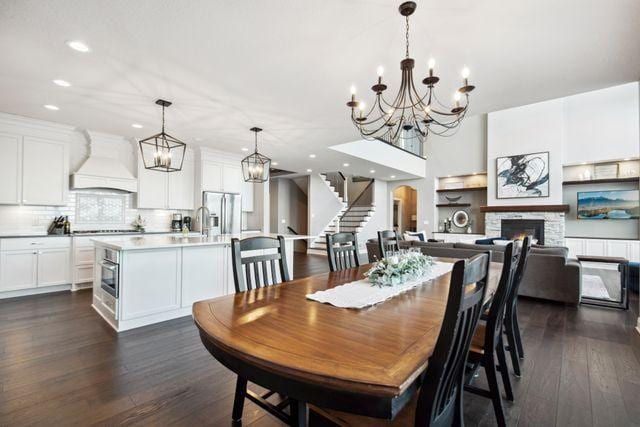 19803 Jersey Ave, Lakeville, MN 55044 - dining area with a chandelier, stairway, dark wood finished floors, recessed lighting, and a fireplace