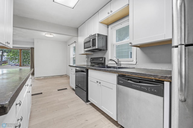 1130 Oak St N, Fargo, ND 58102 - kitchen with stainless steel appliances, dark countertops, white cabinetry, and light wood-style floors