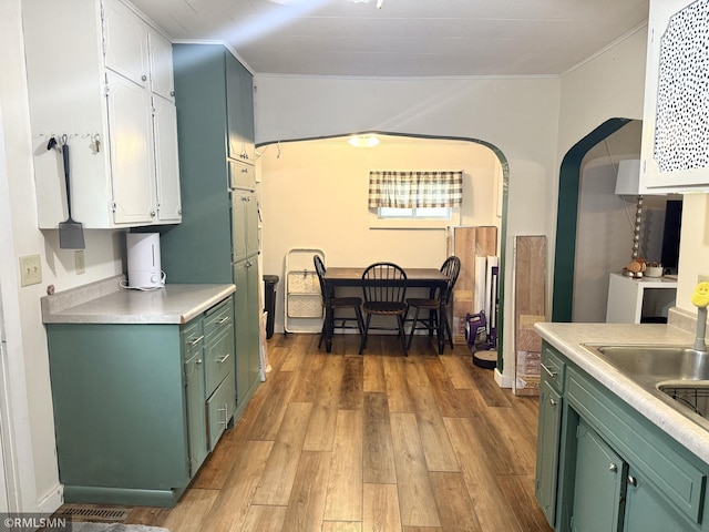208 Cleveland St SE, Silver Lake, MN 55381 - kitchen featuring green cabinets, wood finished floors, light countertops, and ornamental molding