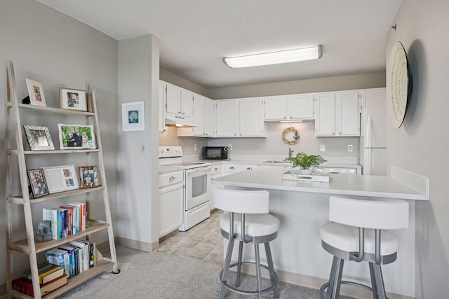 6500 Woodlake Dr Unit 1006, Richfield, MN 55423 - kitchen with white appliances, under cabinet range hood, a peninsula, white cabinetry, and light countertops
