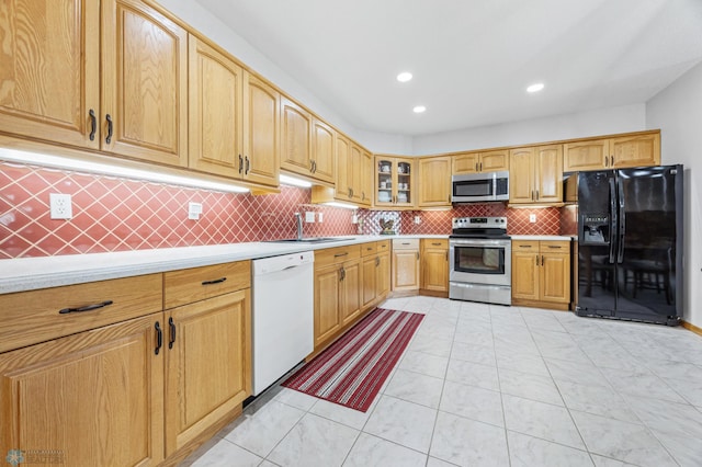 2501 30th Ave S Unit 203, Fargo, ND 58103 - kitchen featuring appliances with stainless steel finishes, light countertops, glass insert cabinets, decorative backsplash, and recessed lighting