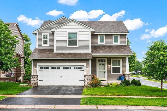 6800 Troy Ln N, Maple Grove, MN 55311 - craftsman house featuring driveway, a front lawn, a garage, covered porch, and roof with shingles