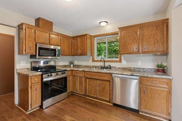 4552 131st St, Savage, MN 55378 - kitchen with stainless steel appliances, dark wood-style floors, brown cabinets, a textured ceiling, and light countertops