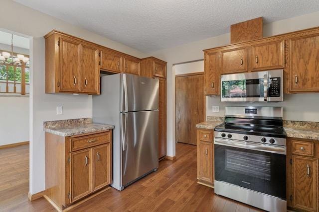 4552 131st St, Savage, MN 55378 - kitchen with stainless steel appliances, dark wood-style floors, brown cabinets, and a textured ceiling