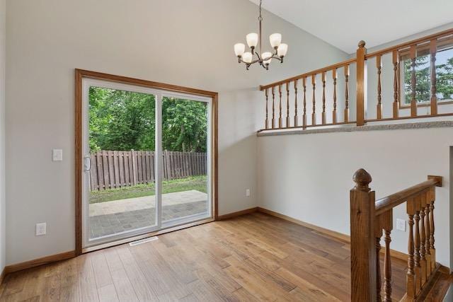 4552 131st St, Savage, MN 55378 - unfurnished room with wood finished floors, plenty of natural light, a chandelier, and vaulted ceiling