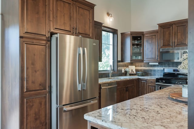 2820 Overlook Dr, Bloomington, MN 55431 - kitchen featuring appliances with stainless steel finishes, tasteful backsplash, light stone countertops, and glass insert cabinets