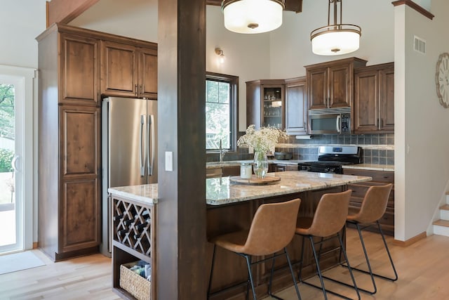 2820 Overlook Dr, Bloomington, MN 55431 - kitchen featuring appliances with stainless steel finishes, tasteful backsplash, healthy amount of natural light, light stone counters, and a towering ceiling