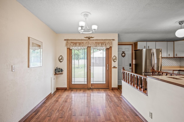 2233 Fremont Ave E, Saint Paul, MN 55119 - unfurnished dining area featuring wood finished floors, a chandelier, and a textured ceiling