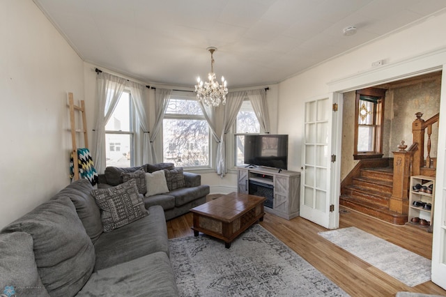 320 Elm St, Crookston, MN 56716 - living room featuring a chandelier, plenty of natural light, wood finished floors, stairs, and crown molding