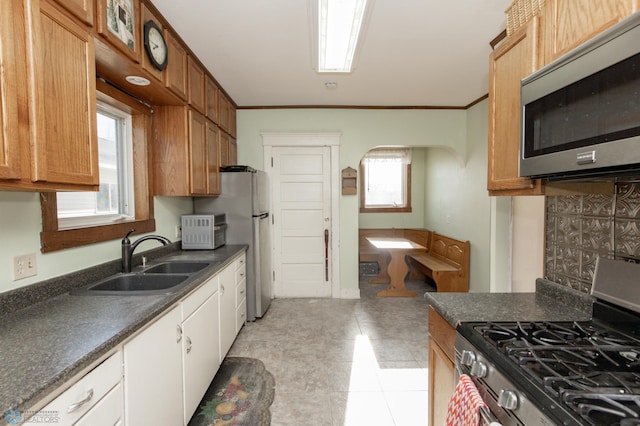 320 Elm St, Crookston, MN 56716 - kitchen featuring stainless steel appliances, dark countertops, ornamental molding, arched walkways, and light tile patterned flooring