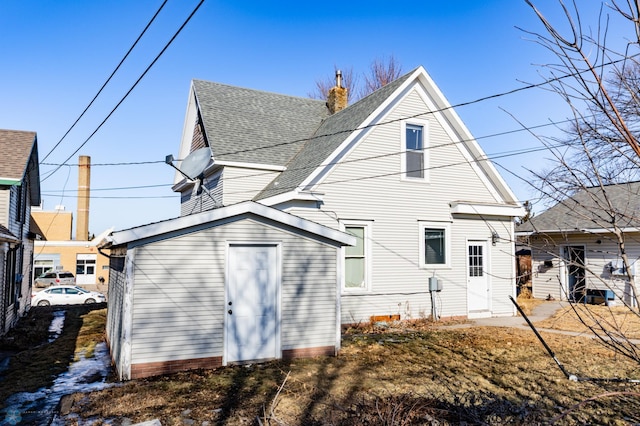320 Elm St, Crookston, MN 56716 - back of house featuring roof with shingles, a chimney, and a storage shed