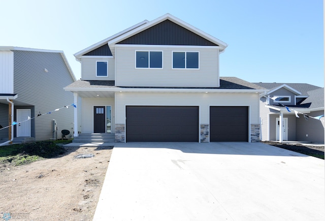 1276 Marlys Dr W, West Fargo, ND 58078 - view of front of home featuring driveway, an attached garage, stone siding, and board and batten siding