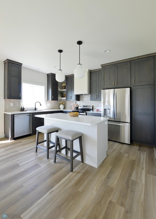 1276 Marlys Dr W, West Fargo, ND 58078 - kitchen with appliances with stainless steel finishes, open shelves, a center island, decorative backsplash, and light wood-style floors