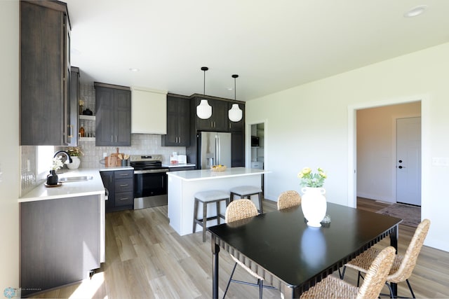 1276 Marlys Dr W, West Fargo, ND 58078 - kitchen featuring stainless steel appliances, light countertops, a kitchen island, backsplash, and light wood-style floors