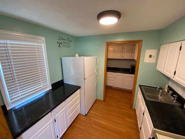 108 20th St S, Benson, MN 56215 - kitchen featuring freestanding refrigerator, white cabinetry, light wood-type flooring, and dark countertops