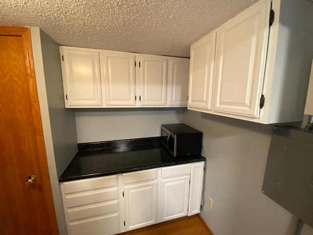 108 20th St S, Benson, MN 56215 - kitchen with stainless steel microwave, white cabinets, dark countertops, and a textured ceiling