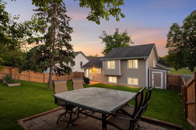 3872 Westbury Ln, Eagan, MN 55123 - back of property at dusk featuring a fenced backyard, a storage unit, outdoor dining area, and a patio area