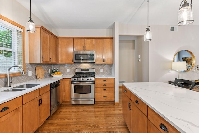 2061 Langston Ln NE, Saint Michael, MN 55376 - kitchen with appliances with stainless steel finishes, brown cabinets, wood finished floors, tasteful backsplash, and light stone countertops