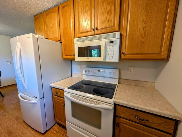314 11th St, Montevideo, MN 56265 - kitchen featuring white appliances, light wood finished floors, light countertops, brown cabinets, and a textured ceiling