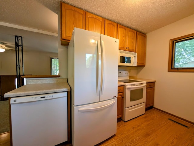 314 11th St, Montevideo, MN 56265 - kitchen featuring white appliances, light wood-type flooring, a textured ceiling, brown cabinets, and light countertops