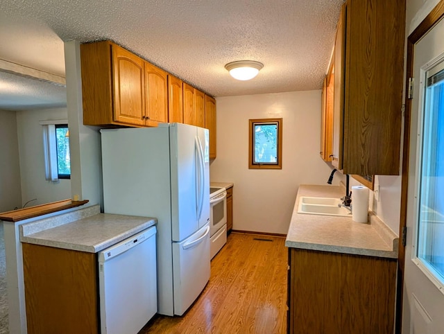 314 11th St, Montevideo, MN 56265 - kitchen featuring white appliances, a textured ceiling, light wood-type flooring, brown cabinets, and light countertops