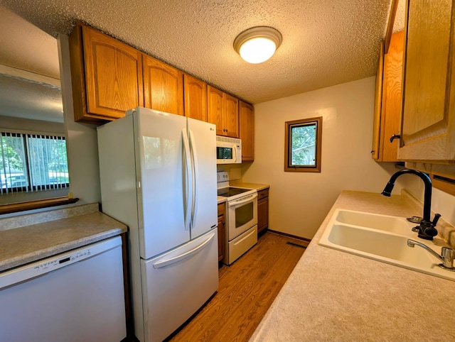 314 11th St, Montevideo, MN 56265 - kitchen with white appliances, a textured ceiling, plenty of natural light, brown cabinetry, and dark wood-style flooring