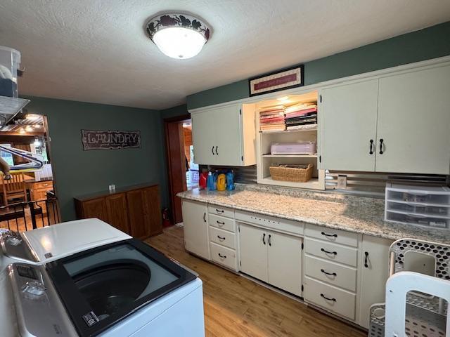 14717 State 210, Stowe Prairie Twp, MN 56453 - kitchen featuring washer / clothes dryer, light wood-type flooring, and white cabinets