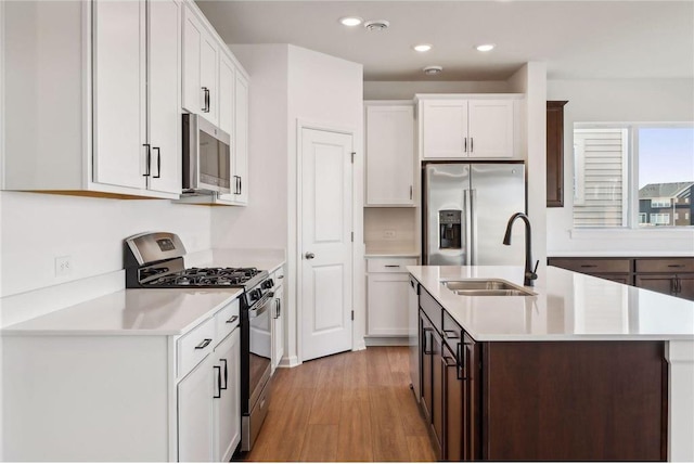 kitchen with stainless steel appliances, light countertops, light wood-style floors, a kitchen island with sink, and recessed lighting