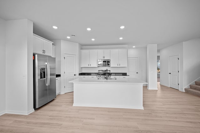 kitchen featuring appliances with stainless steel finishes, white cabinets, light wood-type flooring, recessed lighting, and a kitchen island with sink