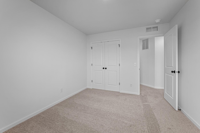 unfurnished bedroom featuring light carpet and a closet