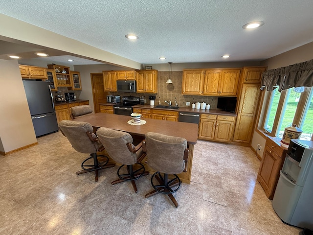 411 Vernon Ave, Morgan, MN 56266 - kitchen featuring stainless steel appliances, brown cabinets, backsplash, a textured ceiling, and a kitchen bar