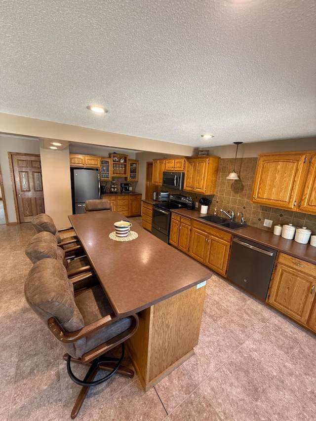 411 Vernon Ave, Morgan, MN 56266 - kitchen with appliances with stainless steel finishes, brown cabinets, a center island, a kitchen breakfast bar, and a textured ceiling