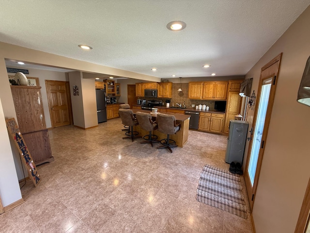 411 Vernon Ave, Morgan, MN 56266 - kitchen with black appliances, brown cabinetry, a kitchen breakfast bar, a center island, and recessed lighting