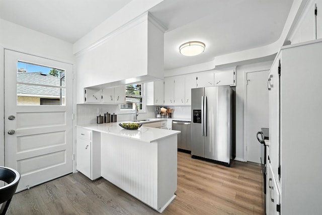 1464 Kent St, Saint Paul, MN 55117 - kitchen featuring stainless steel appliances, a peninsula, light wood finished floors, tasteful backsplash, and white cabinetry